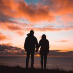 Silhouette photo of man and woman on cliff while sunset