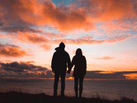 Silhouette photo of man and woman on cliff while sunset