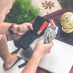 Man holding a leather wallet with some US dollars