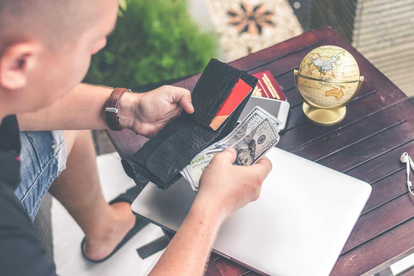 Man holding a leather wallet with some US dollars