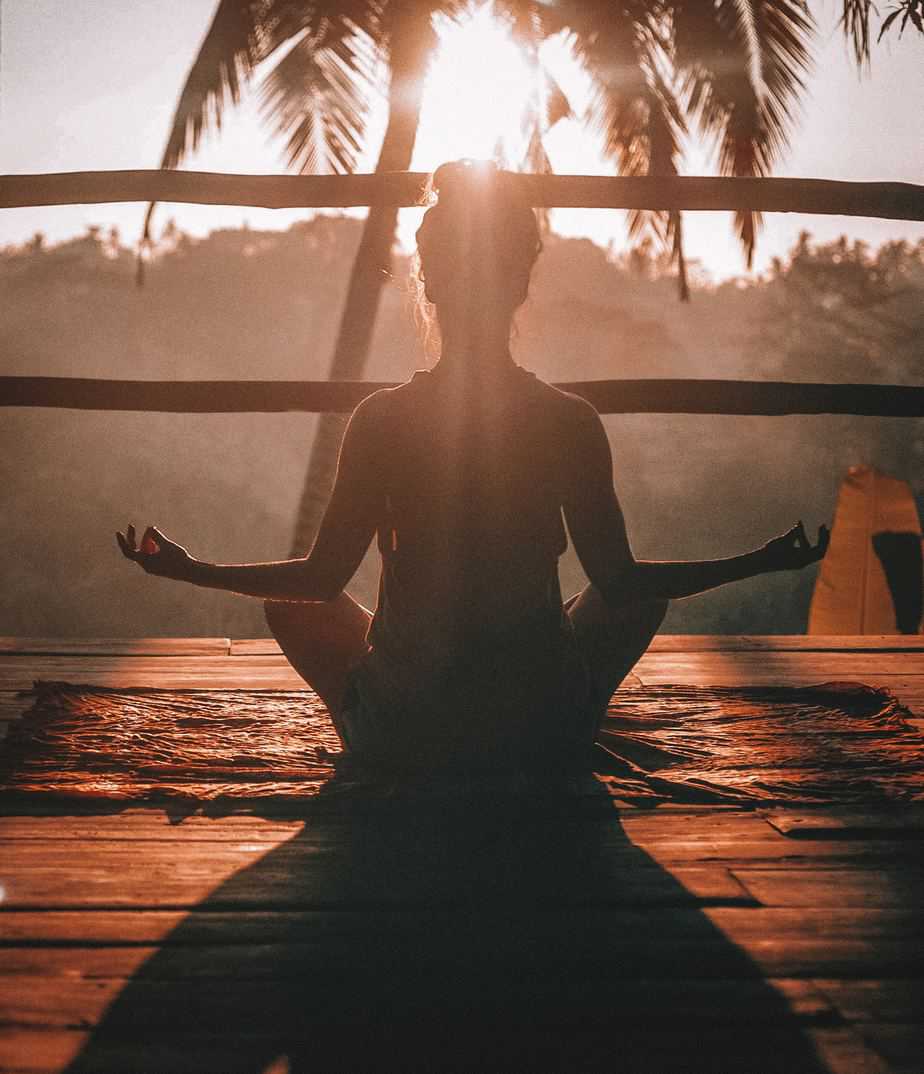 Woman doing yoga meditation on brown parquet flooring during daytime