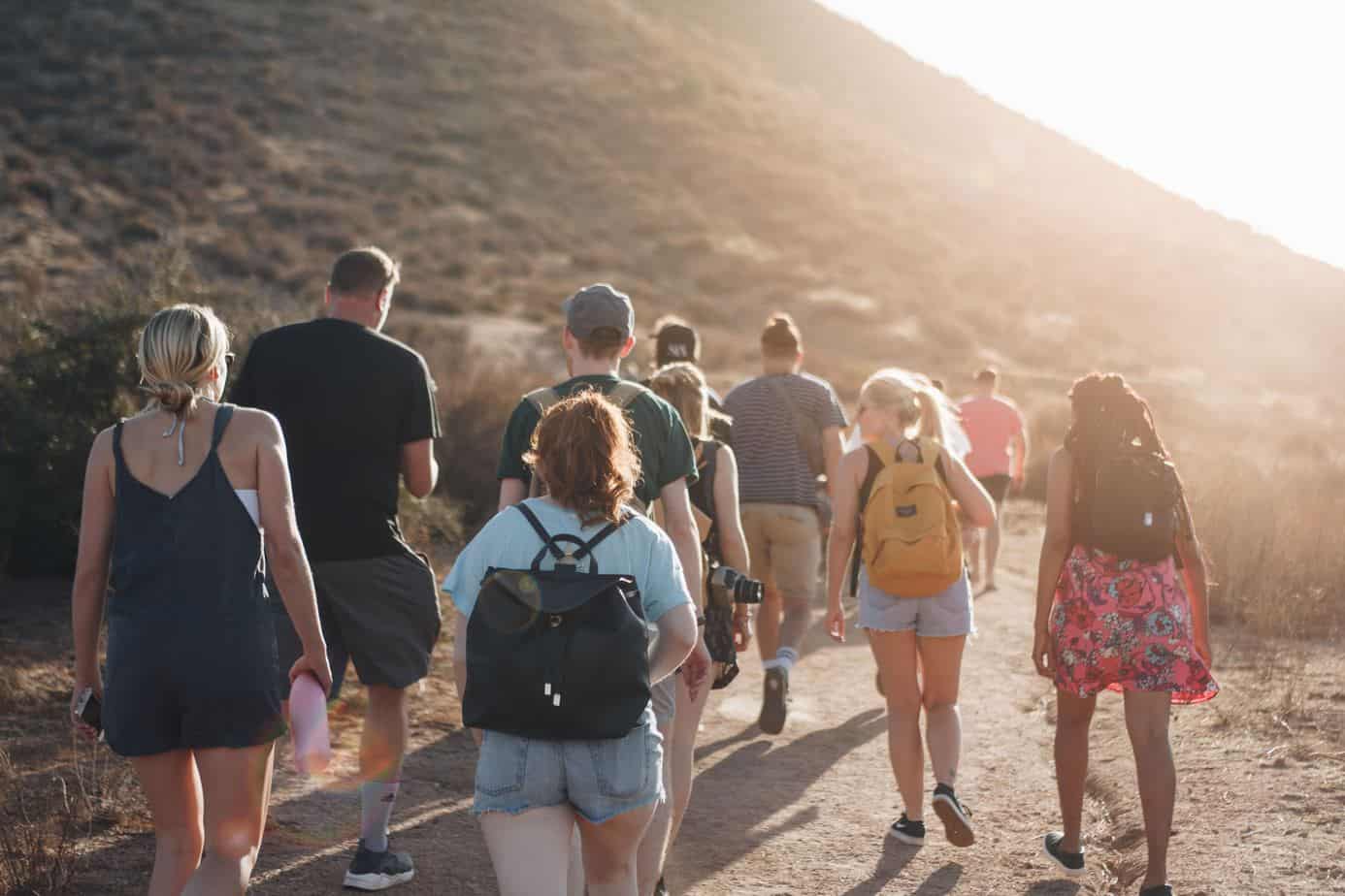 People walking on dirt road near mountain during daytime