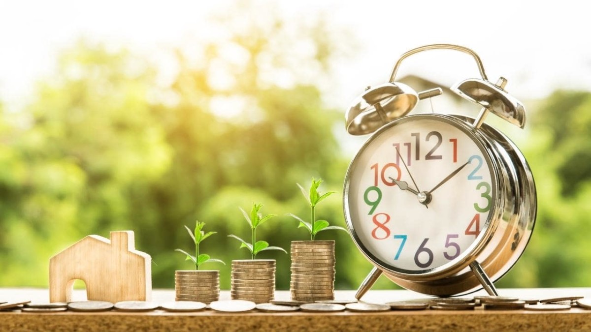 Plants growing on coin piles next to an alarm clock