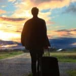 man holding a suitcase during sunset