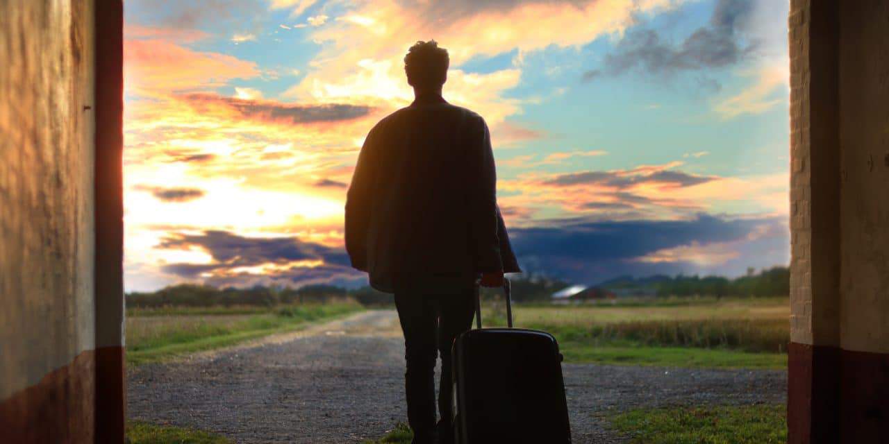 man holding a suitcase during sunset