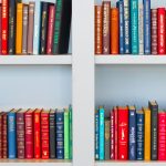 Lots of books placed on white wooden shelf