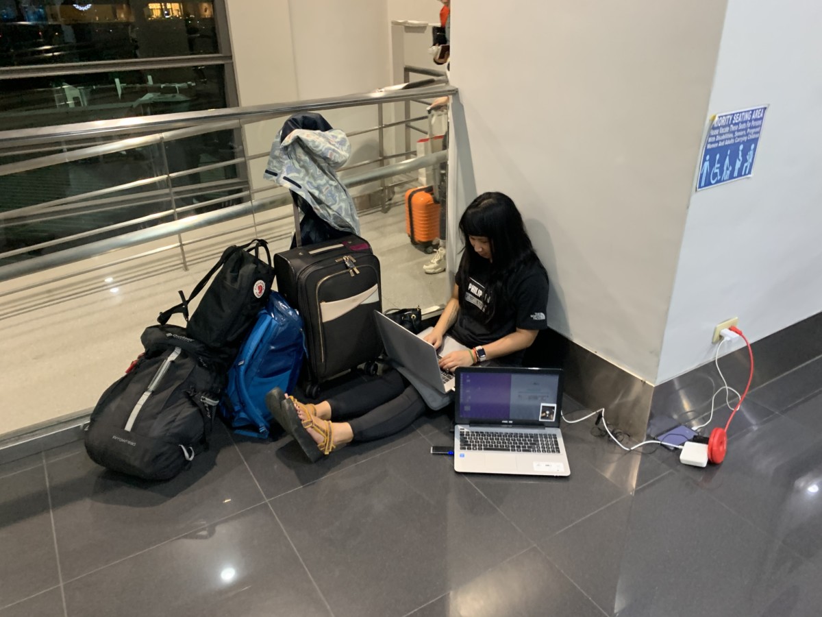 Jessica Ayre sitting at the airport and working on her laptop