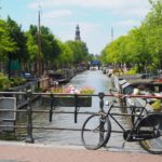 black bike parked beside river during daytime in Netherlands