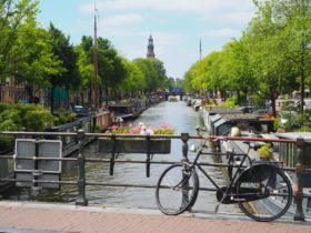 black bike parked beside river during daytime in Netherlands