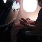 Person with mask using phone in airplane