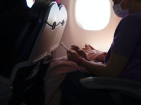 Person with mask using phone in airplane