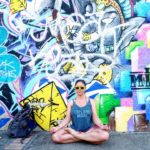 Jade doing yoga in front of a wall with graffiti