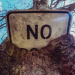 A street sign that says no buried inside of a tree.