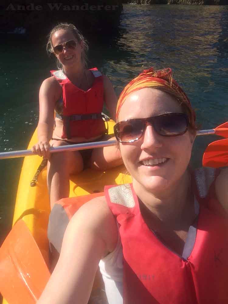 Ande wanderer and her friend kerry hunter sit in a yellow double kayak on the water while both wearing red life jackets