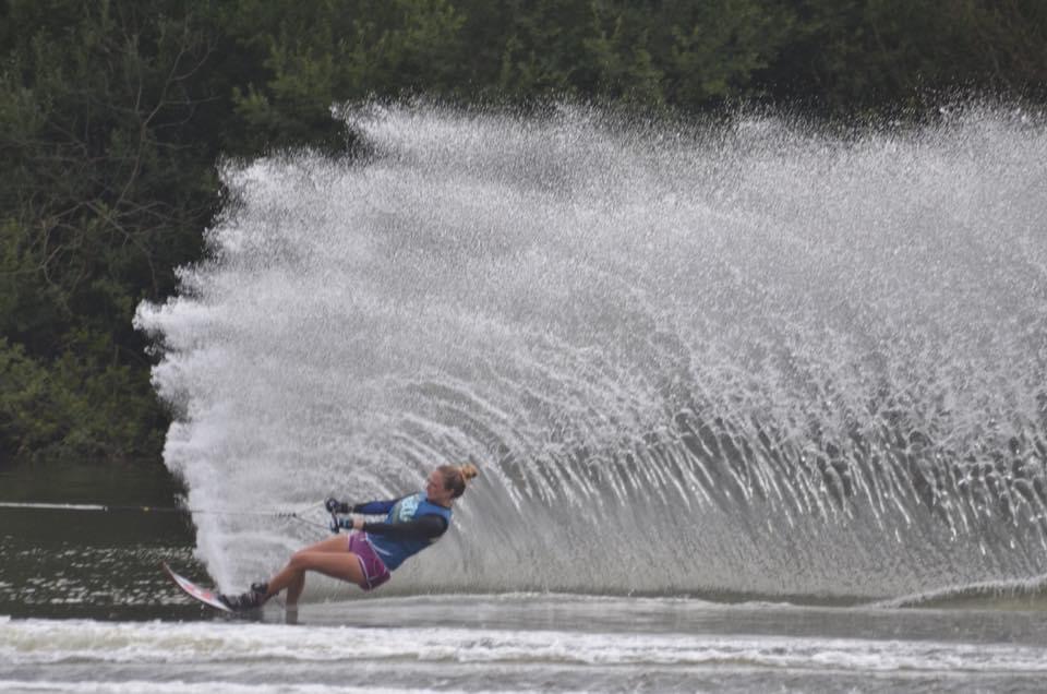 Anny Wooldridge water skiing with a large wave spray behind her