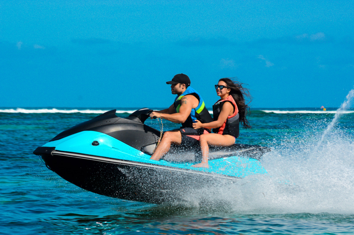 Phillip Lew driving a jet ski on the ocean with a female sitting behind him