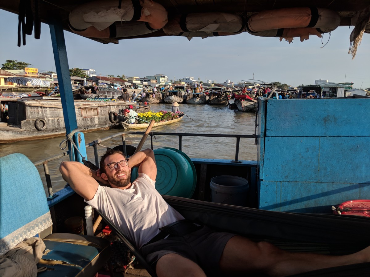 Daniel Rusteen laying on a chair on a boat in a floating market