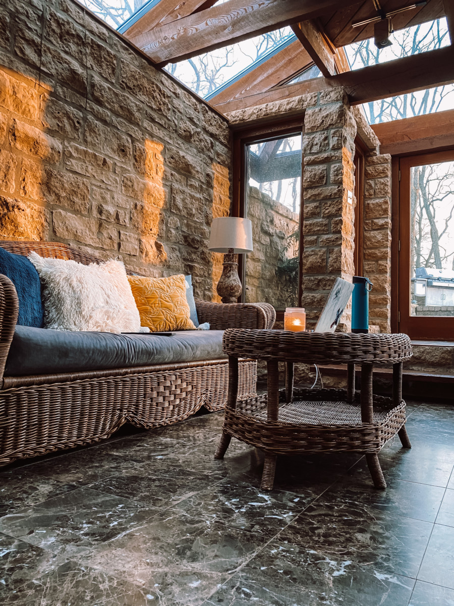 the living room of an airbnb amy suto lived in in Galena with all stone walls and a wicker couch with sunlight coming through the windows