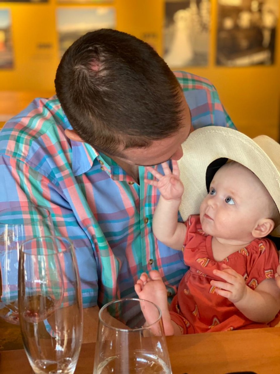 Brian Davis sits at a table with his daughter while she wears an oversized hat