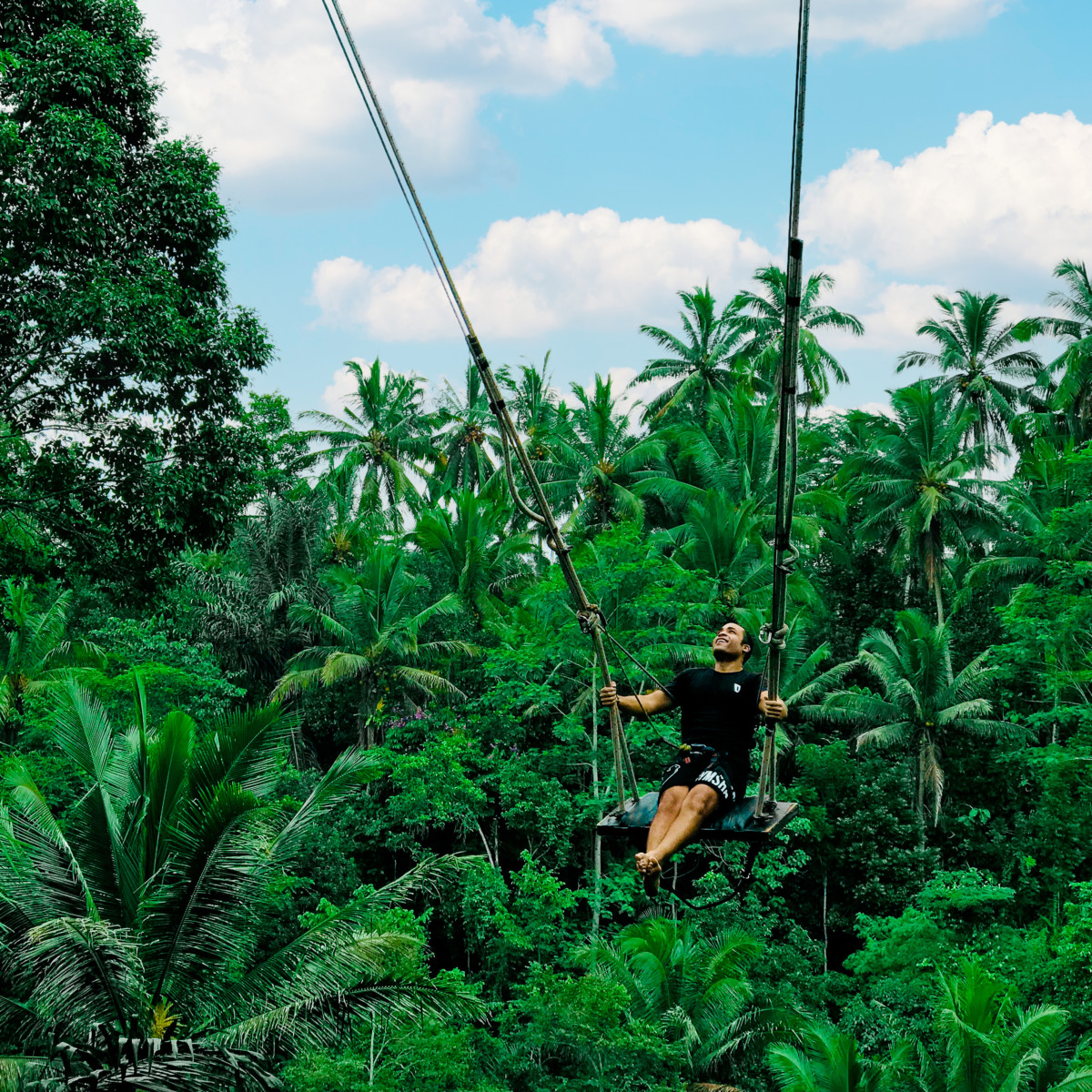 Phillip Lew on a large swing swinging over the jungle