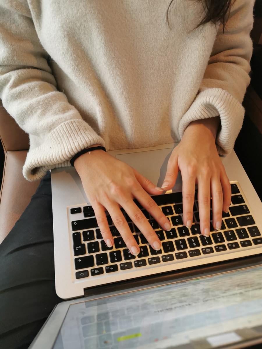 Looking down on Nina Clapperton's laptop keyboard as she has both hands on the keyboard