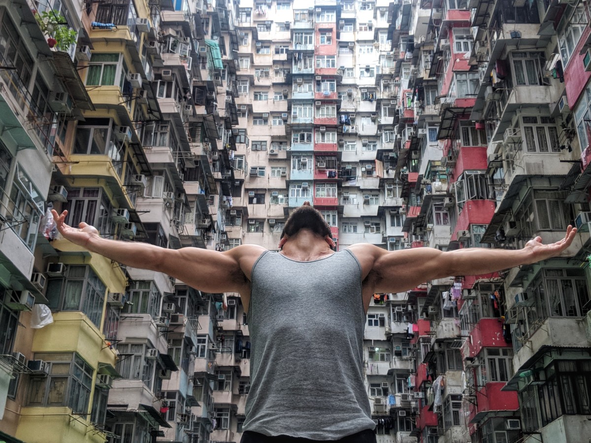 Daniel Rusteen looking to the sky with arms wide open in a courtyard of apartment buildings in Hong Kong