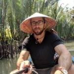 Daniel Rusteen on a river canoe in the jungle wearing a domed hat