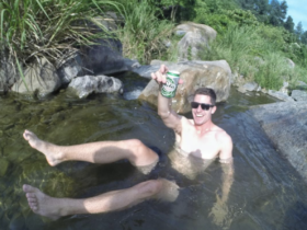 Cam Woodsum smiling and enjoying a beer in a sunny day in the lake