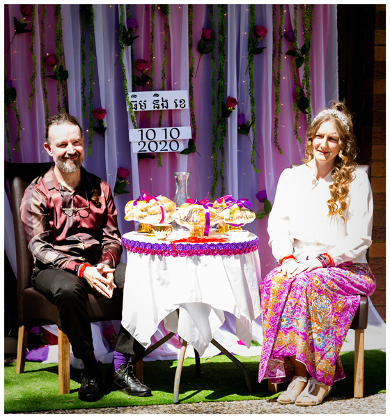 Tim and Kassandra Marsh sit at an adorned circular table in Cambodia for their Cambodian wedding ceremony