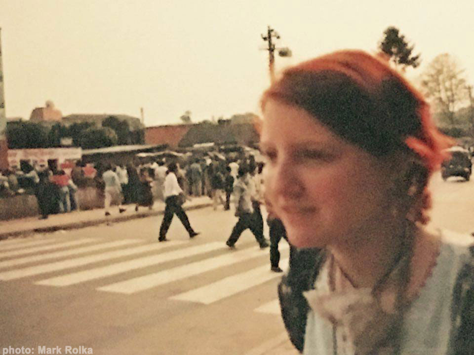 Ande wanderer stands near a crosswalk of a street in kathmandu, nepal and several pedestrians cross the street 