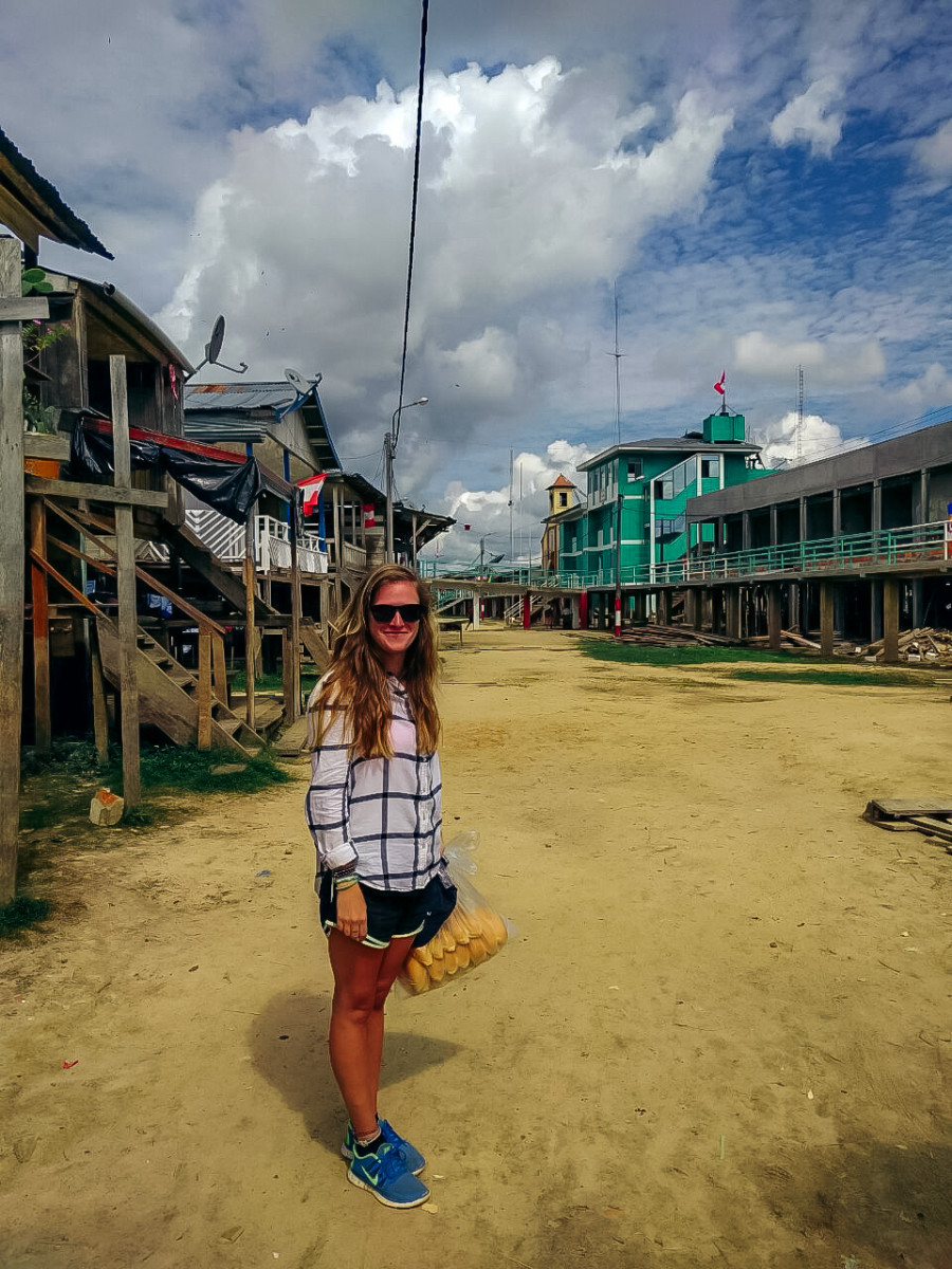 Anny Wooldridge standing on an empty dirt road in a village in Peru with homes on both sides of the road