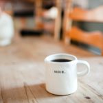 a white mug with the word begin is sitting on a wooden table