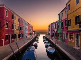 Blue boats parked on river between multicolored buildings in the middle of a city