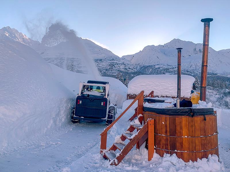 wooden hot tubs sit in deep snow with staircases leading up to them in valdez, alaska