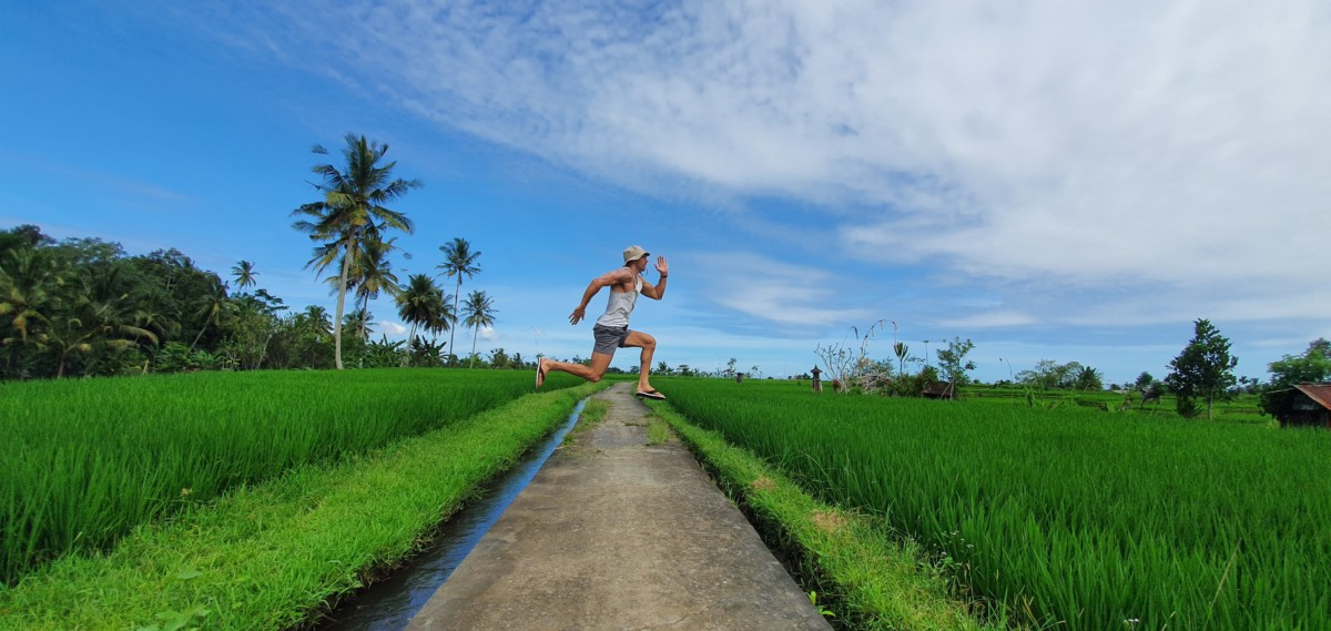 Daniel Rusteen in Ubud, Bali jumping in the air from a street in the middle of rice paddies