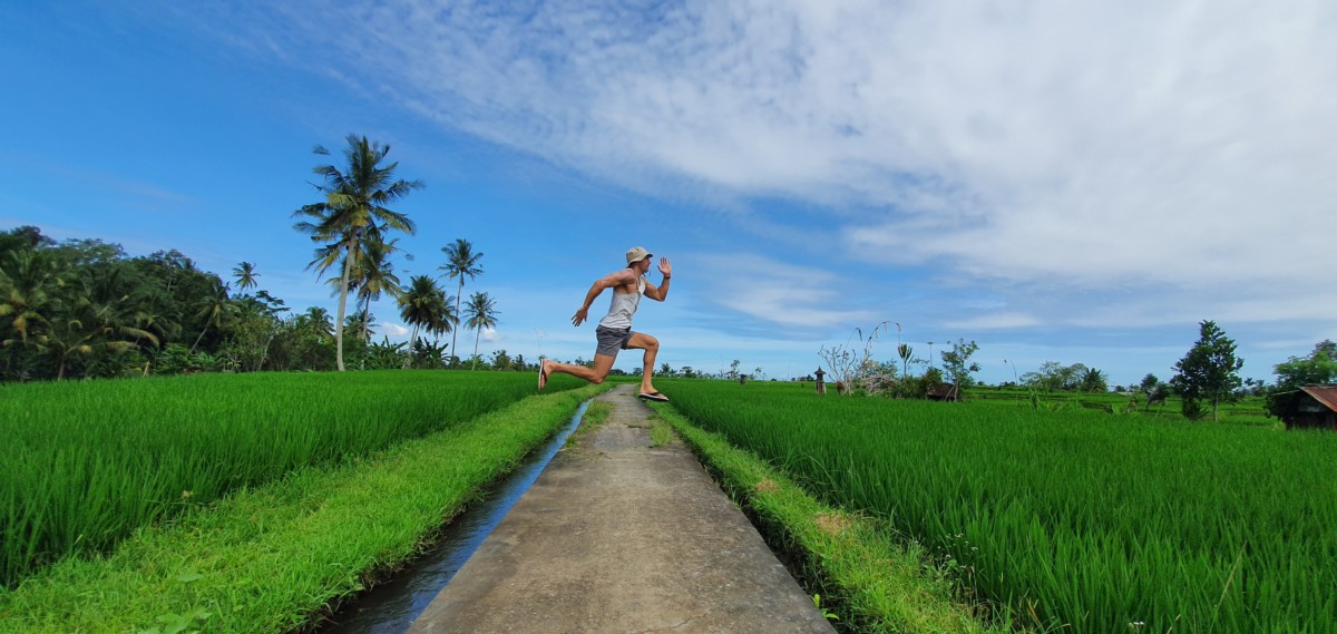 Daniel Rusteen in Ubud, Bali jumping in the air from a street in the middle of rice paddies