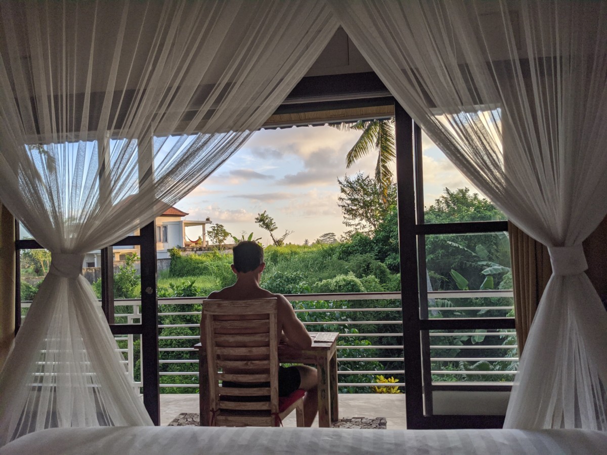 Daniel Rusteen sitting on a chair on a patio in Ubud, Bali looking out over the jungle