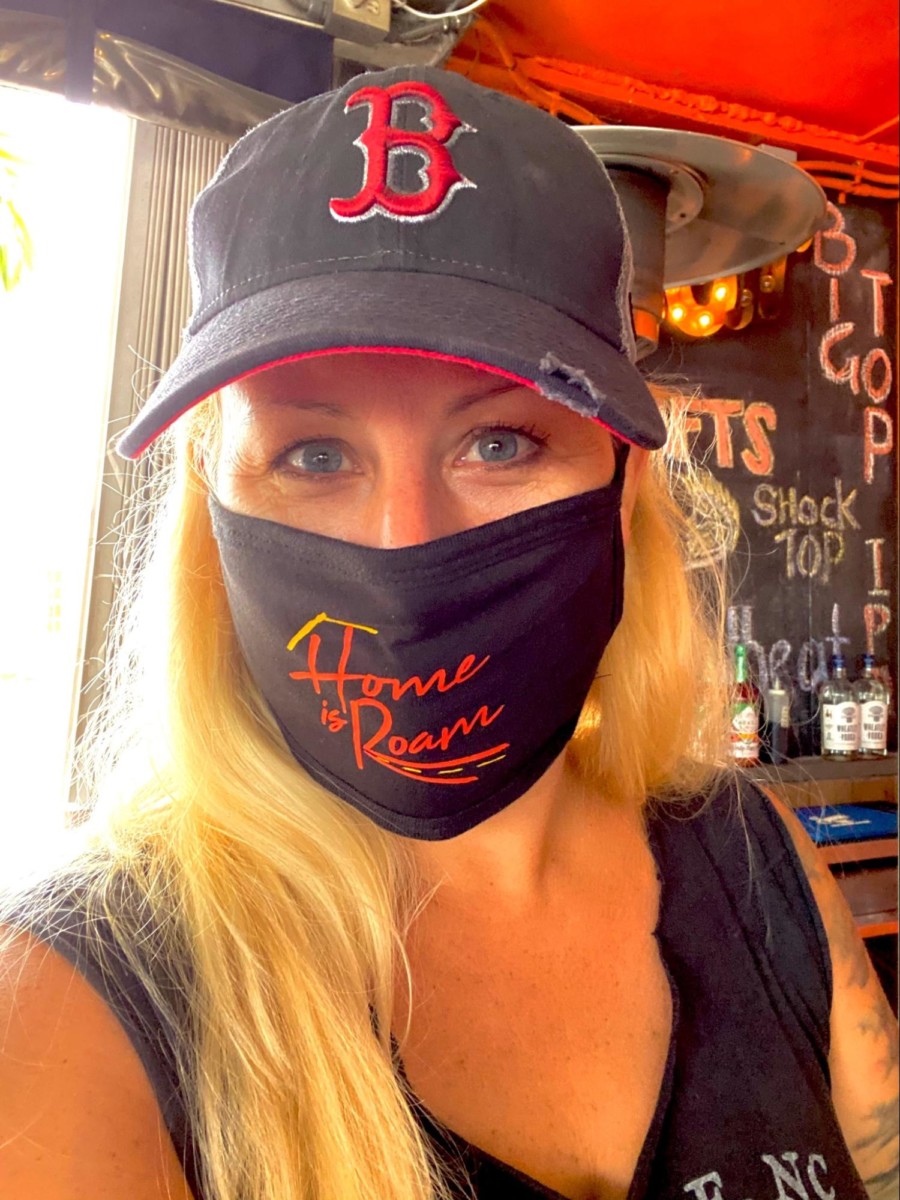 Angela Faith Martin looking at the camera while wearing a Boston Red Socks hat and a home is roam face mask