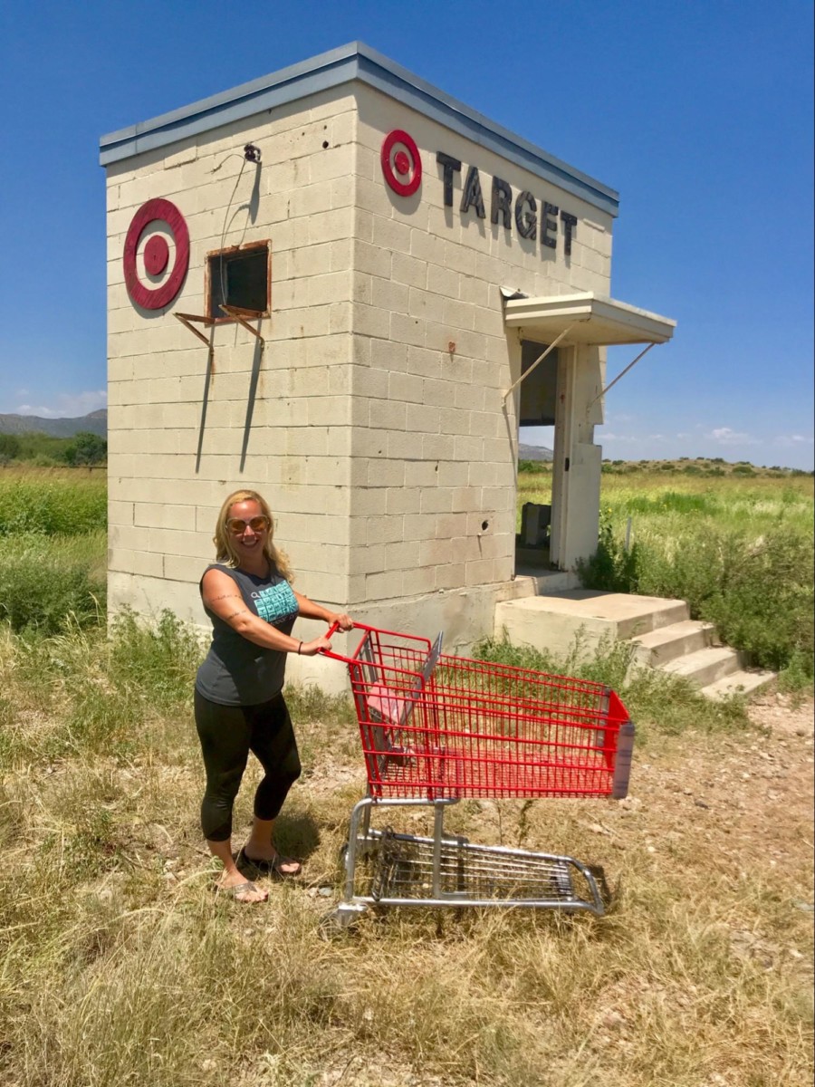 Angela Faith Martin pushing a shopping cart in front of a fake, tiny Target store in a field