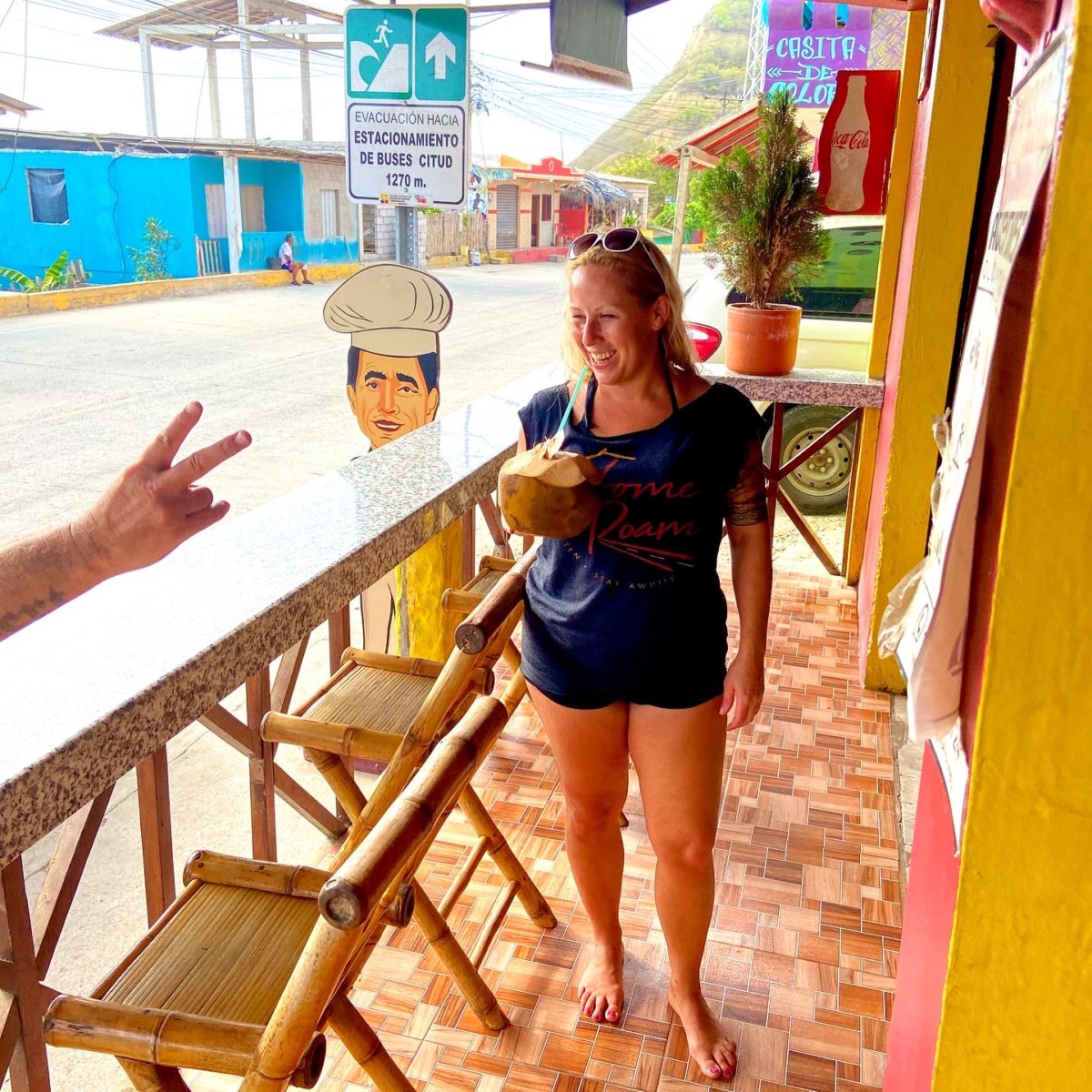 Angela Faith Martin standing on a patio while drinking out of a coconut