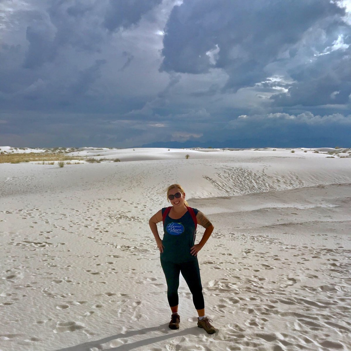 Angela Faith Martin standing in sand with dark clouds above her