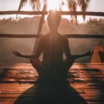 A Woman taking a morning yoga session peering into the jungle in Bali.