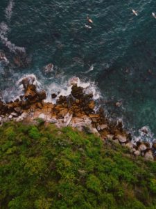 aerial shot of ocean crashing into cliffs