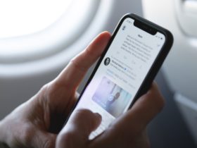 Man holding a smartphone with twitter app opened while in an airplane