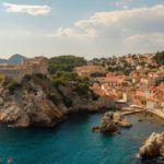 city view of Dubrovnik, croatia, with the ocean in front and the old buildings with orange roofs.