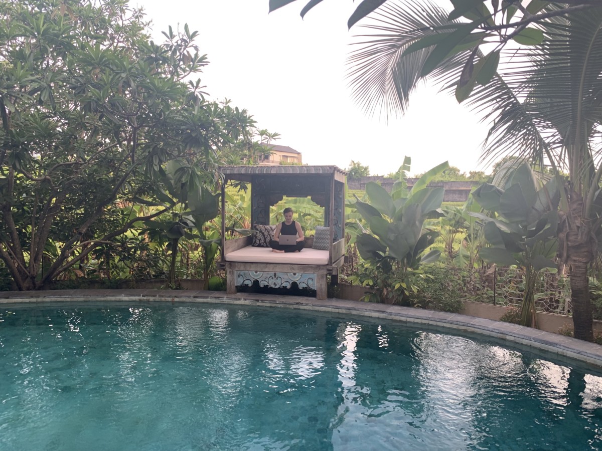 Sarah Archer sits on a covered bed in Bali next to a pool