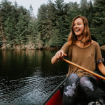 Vivi laughing while rowing in a little boat near the woods