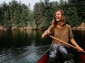 Vivi laughing while rowing in a little boat near the woods