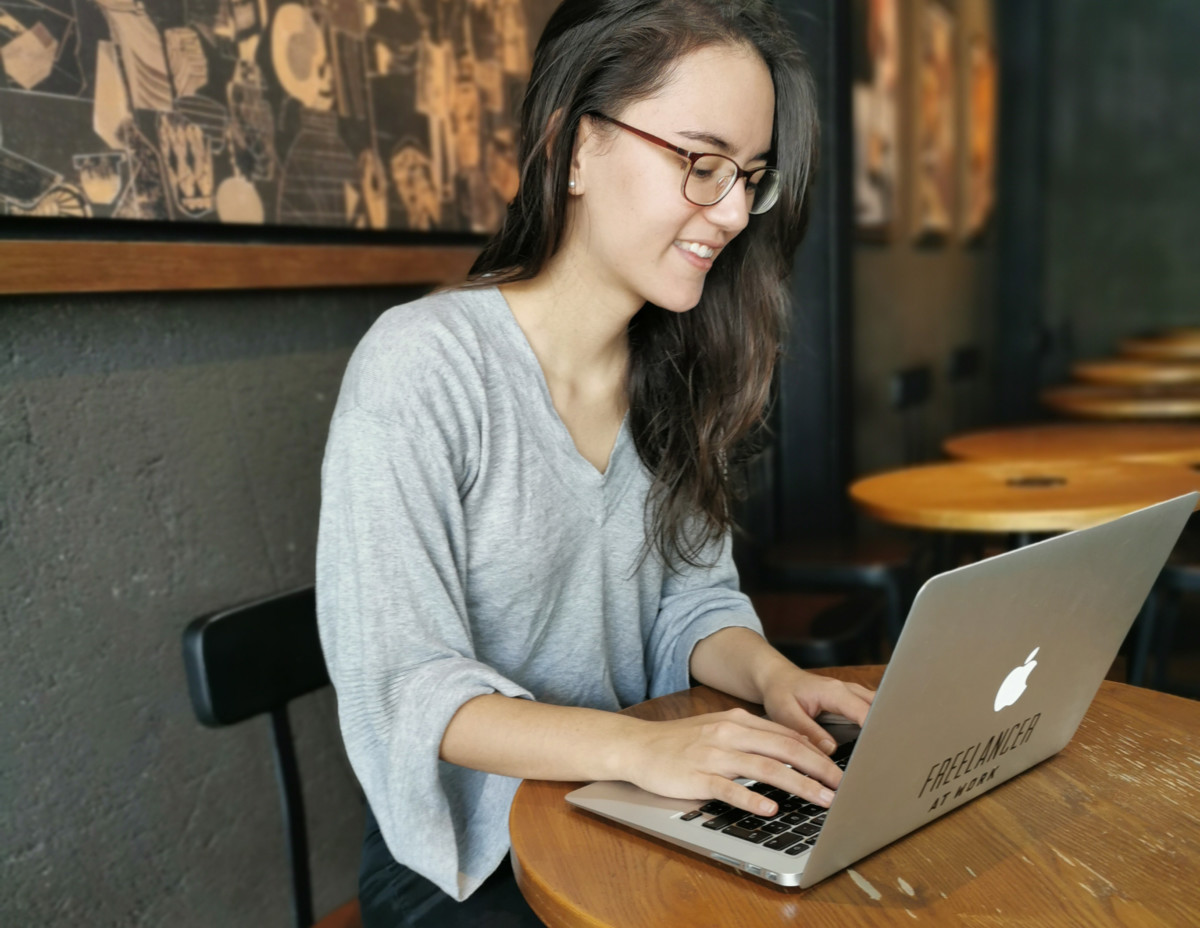 a shot of deya working on her laptop in a cafe wearing a grey sweater