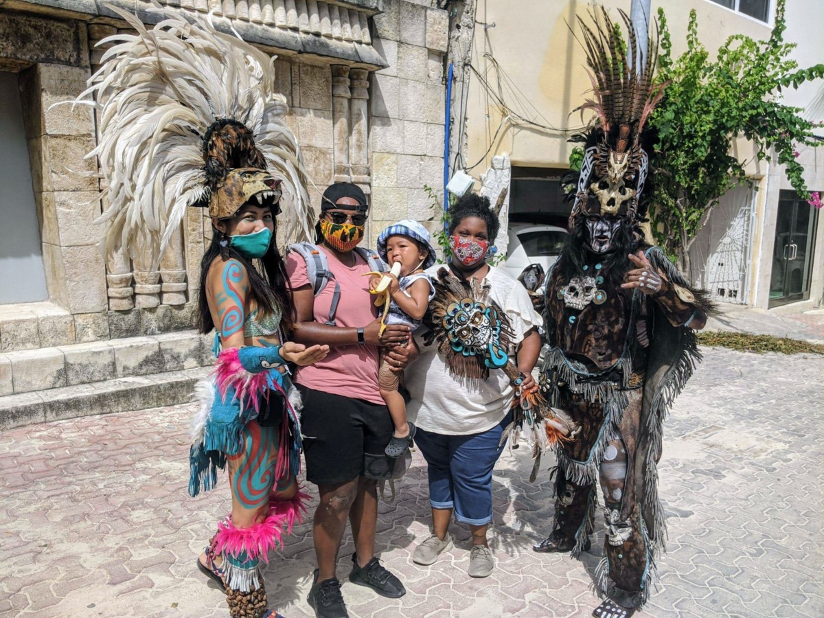 Two women stand holding their small son with two other people next to wear wearing costumes